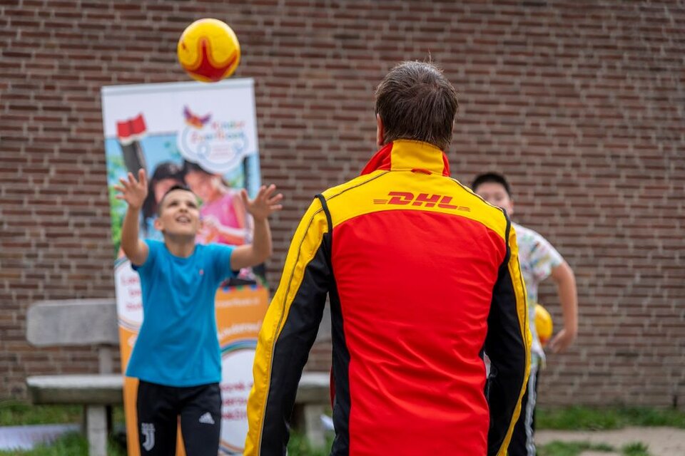DHL volunteer playing football with child
