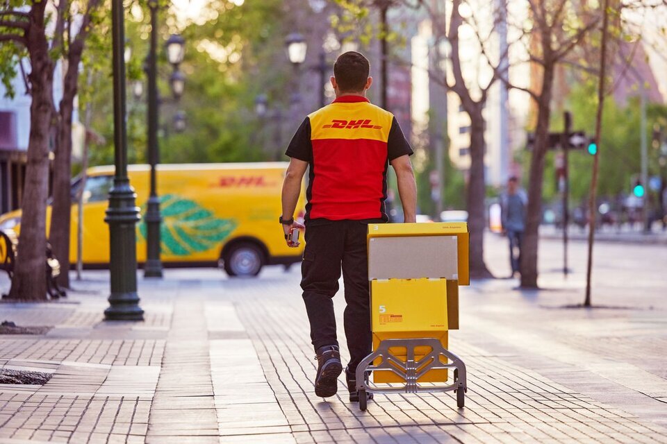 DHL courier walking towards his DHL electric van