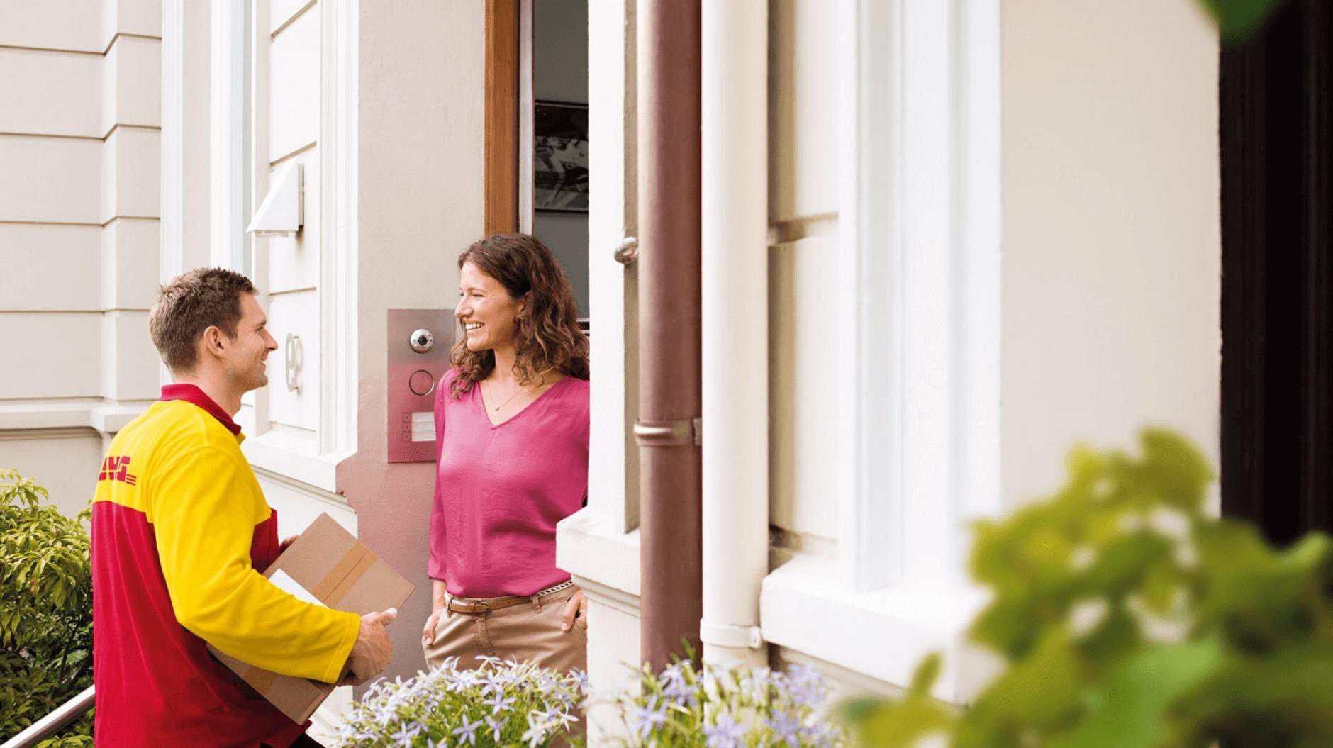 DHL courier delivering parcel to a woman at the door