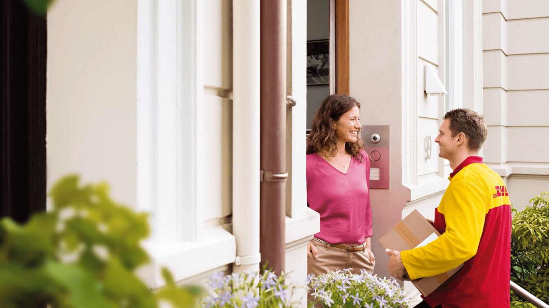 DHL courier delivering parcel to a woman at the door