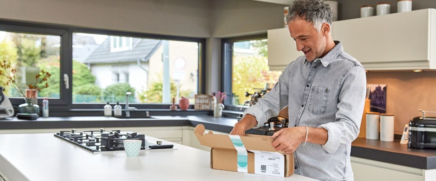 man opening parcel in kitchen